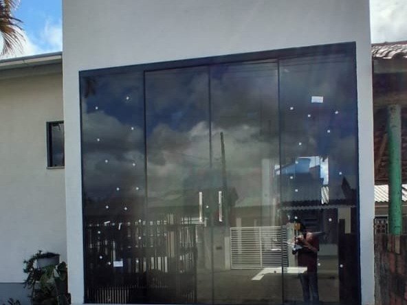Fachada residencial com grandes portas de vidro e esquadrias escuras